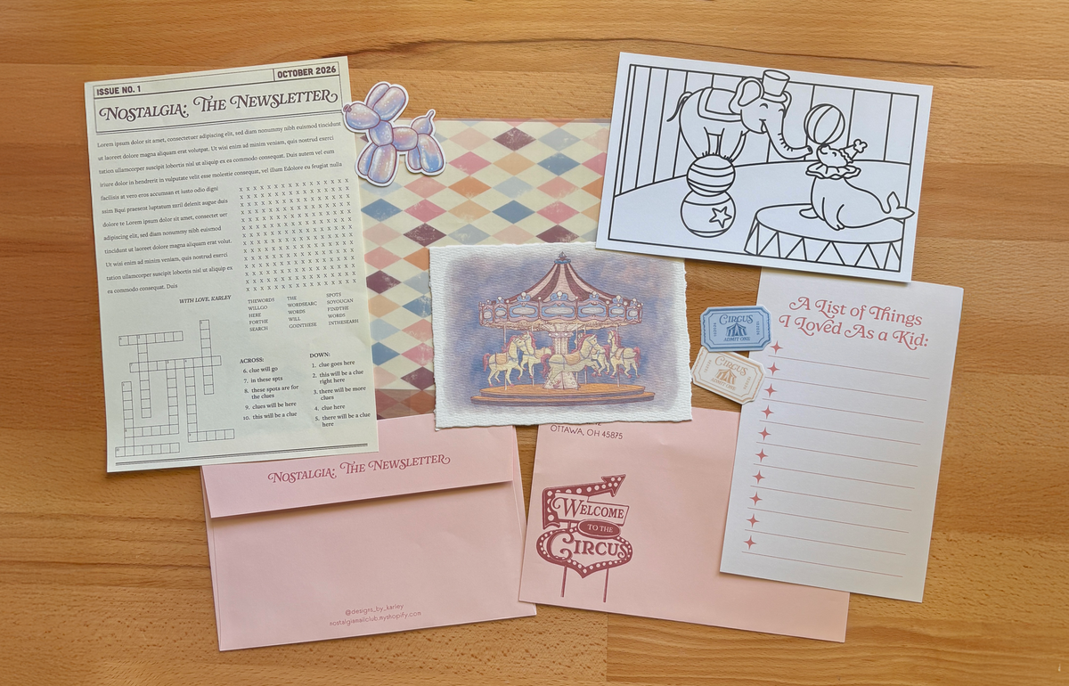 A set of stationery laid out on a wooden table. Contents of a mail club including a newsletter, stickers, an art print of a carousel, a pink envelope, coloring page, and journal prompt